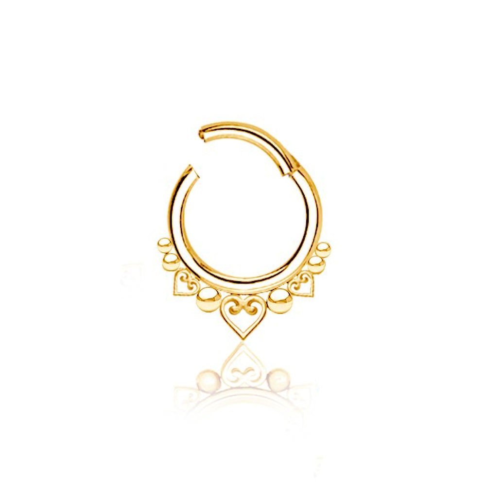 The Liora Minimalist Mandala-Inspired Septum by Kaya Movement boasts a gold hoop design with intricate heart-shaped and circular mandala patterns hanging from the bottom. Crafted from smooth, reflective 316L steel, this elegant piece is available in gauges of 1.2mm and diameters of 6mm, 8mm, and 10mm, casting a delicate shadow on the white background.